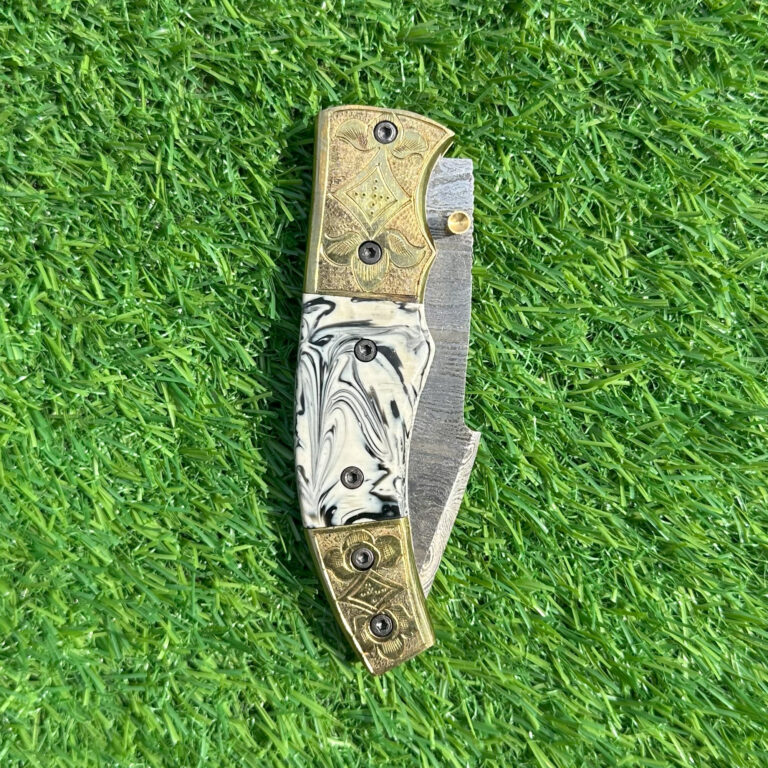 : Hand forged Damascus steel folding knife with engraved brass bolsters and marbled black white handle
