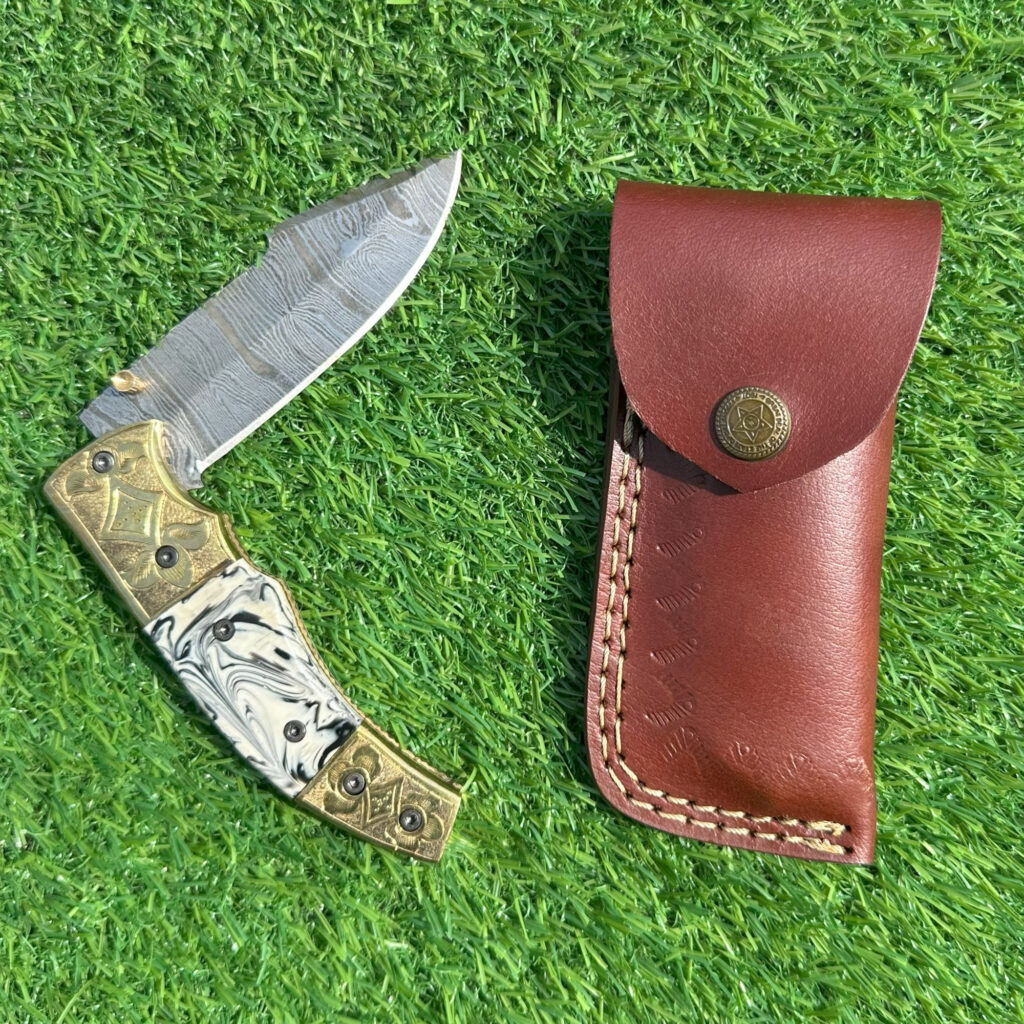 Damascus steel knife blade fully open displaying wave pattern and brass details