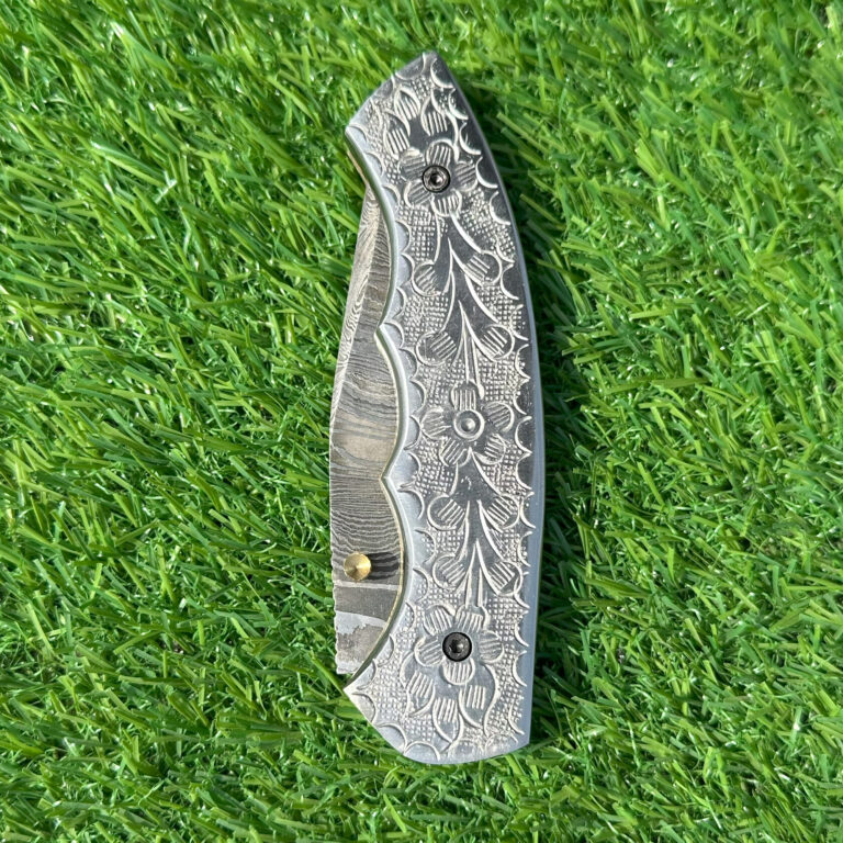 Close-up of hand-engraved floral motifs on full Damascus steel folding knife handle