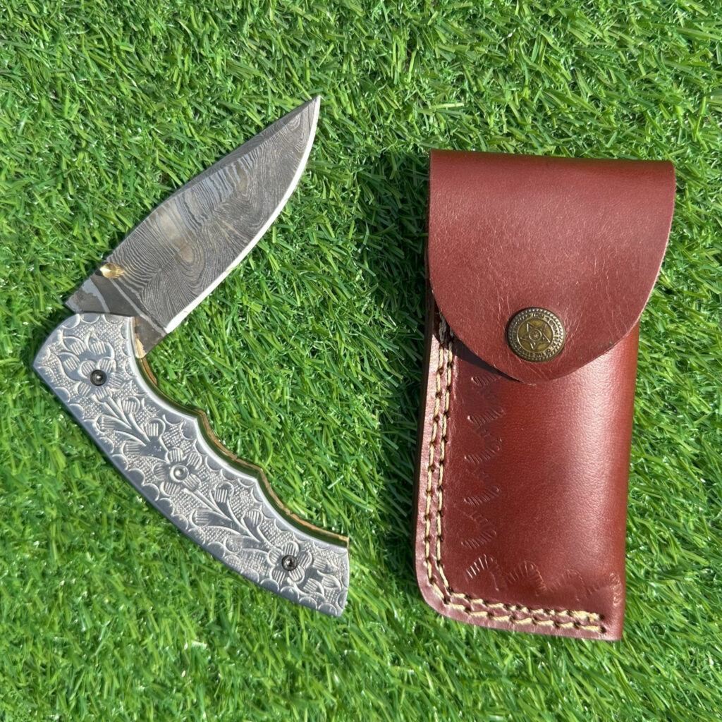Full Damascus steel folding knife with hand-engraved floral handle and premium leather sheath