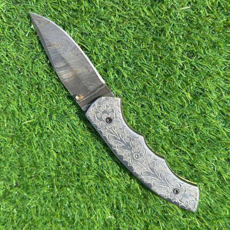 Damascus folding knife showing elaborate hand-carved floral engravings on full Damascus handle