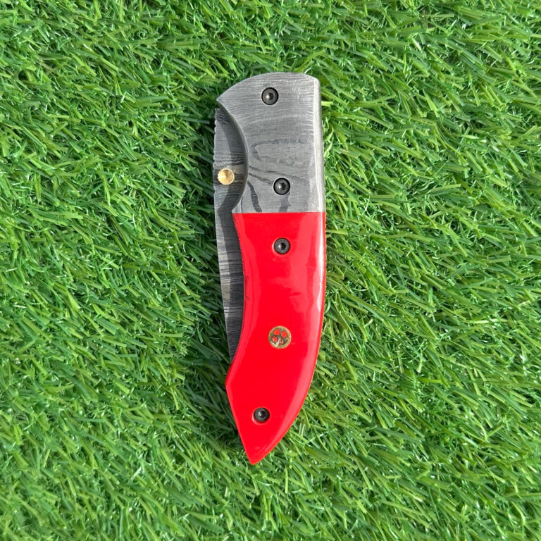Damascus folding knife red handle closed showing brass accents and Damascus bolsters