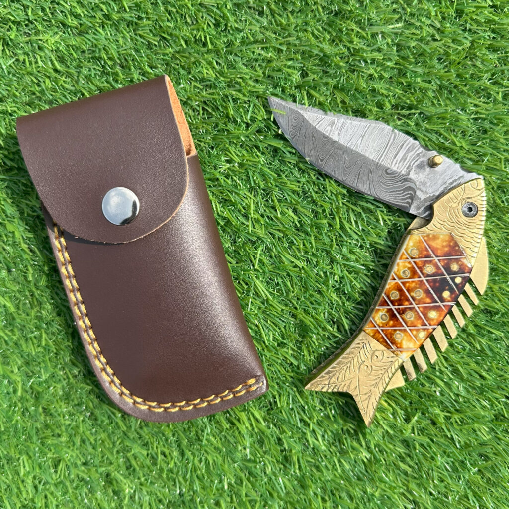 Hand forged Damascus blade open showing wave pattern and engraved brass fish scales